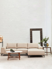 White marble coffee table set on a textured rug in front of a fabric sofa