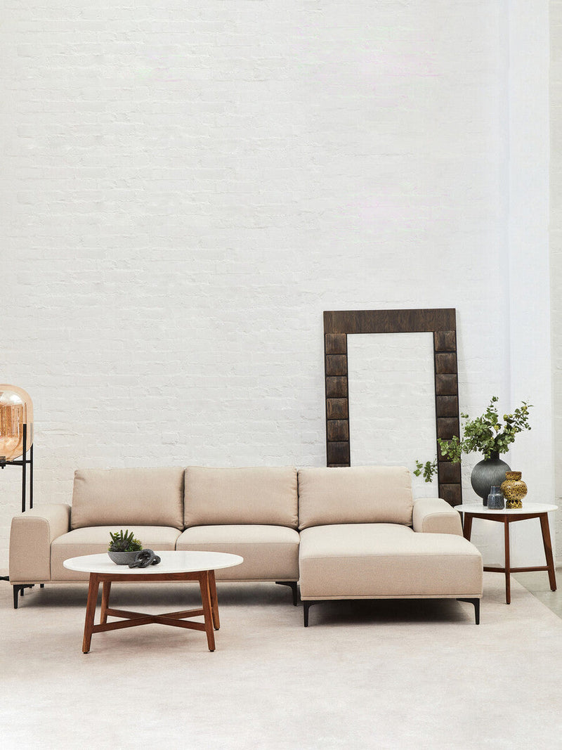 White marble coffee table set on a textured rug in front of a fabric sofa