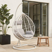White rattan effect hanging chair shown in an outdoor patio setting