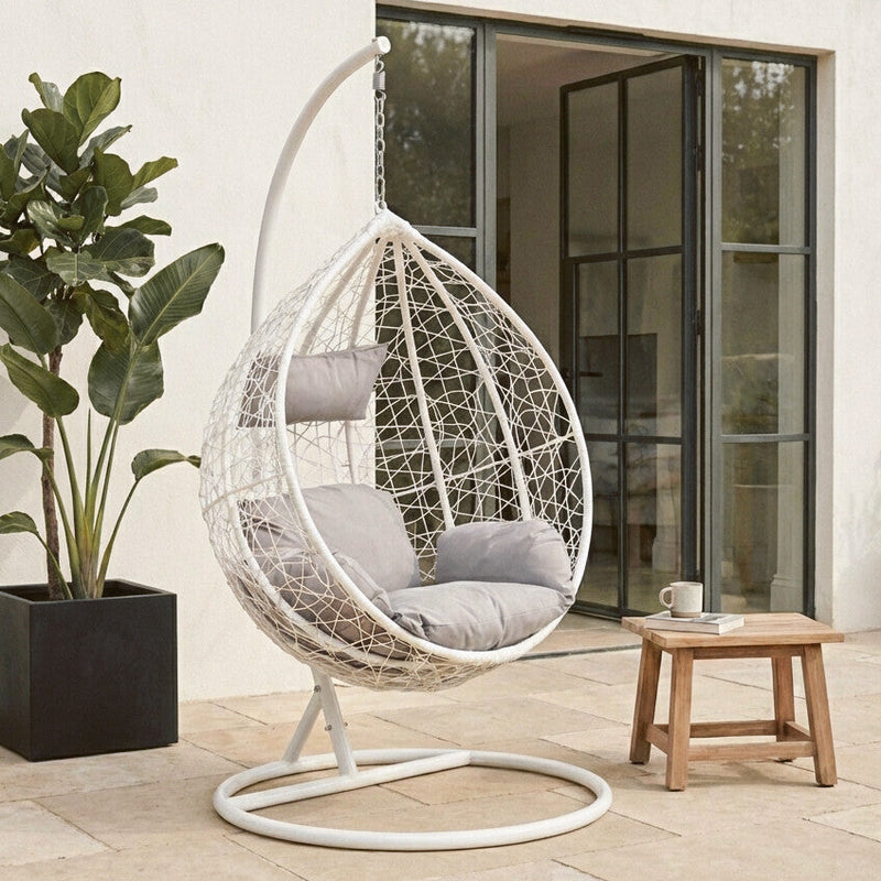 White rattan effect hanging chair shown in an outdoor patio setting