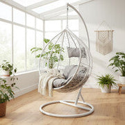 White rattan effect hanging chair styled in a bright sunroom setting