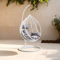 White rattan effect hanging chair with grey cushions styled in a living room