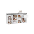 White shoe storage bench with grey padded seat, filled with shoes across nine cubbies and a boot space