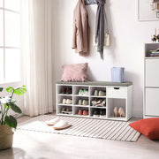 The white shoe bench in a bright entryway below a coat rack, with a cushion on the seat