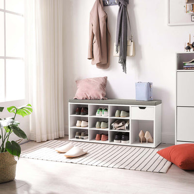 The white shoe bench in a bright entryway below a coat rack, with a cushion on the seat