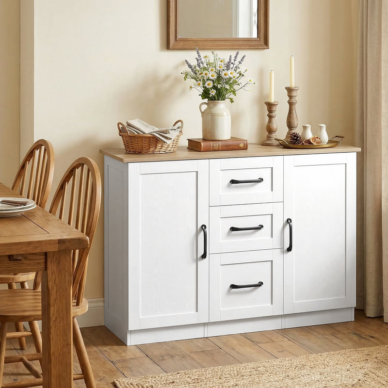 White sideboard against a cream wall in a dining room with flowers and candles on top