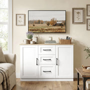 White sideboard under a framed landscape print beside an armchair in a living room