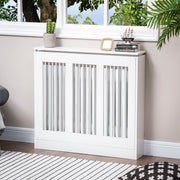 White radiator cover under a window with a plant, books and a photo frame on top