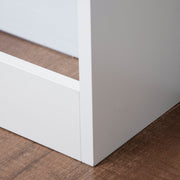 Close-up of the white base corner of the radiator cover on a wood floor