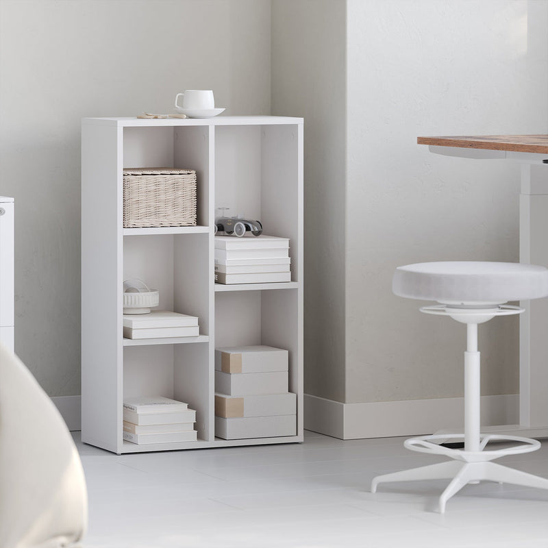 White wooden kids bookcase styled with books and decor in a bedroom