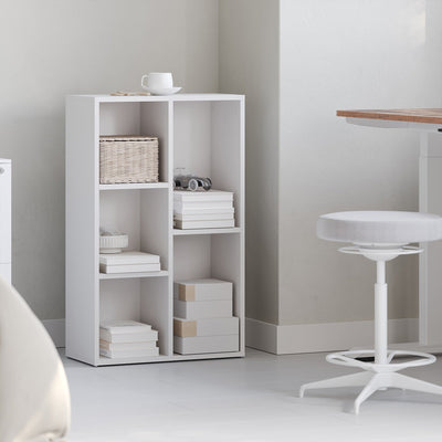 White wooden kids bookcase styled with books and decor in a bedroom