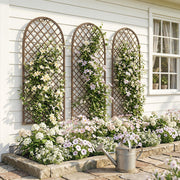 Three wicker trellis panels mounted on a house wall with white and pink climbing flowers