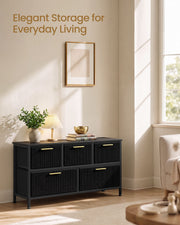 Black corduroy chest styled in a living room under a framed print, holding books and a table lamp