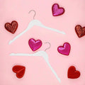 White wood clothes hangers styled flat-lay with heart decorations