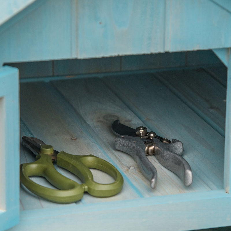 Shears and secateurs on the wooden floor inside the blue sentry box shed