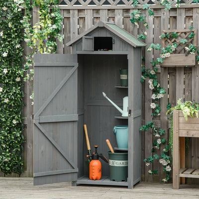 Grey wooden sentry box shed with its door open in a garden, tools and pots stored inside