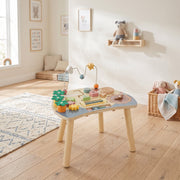 Activity table in a bright playroom on a rug beside a basket and shelf