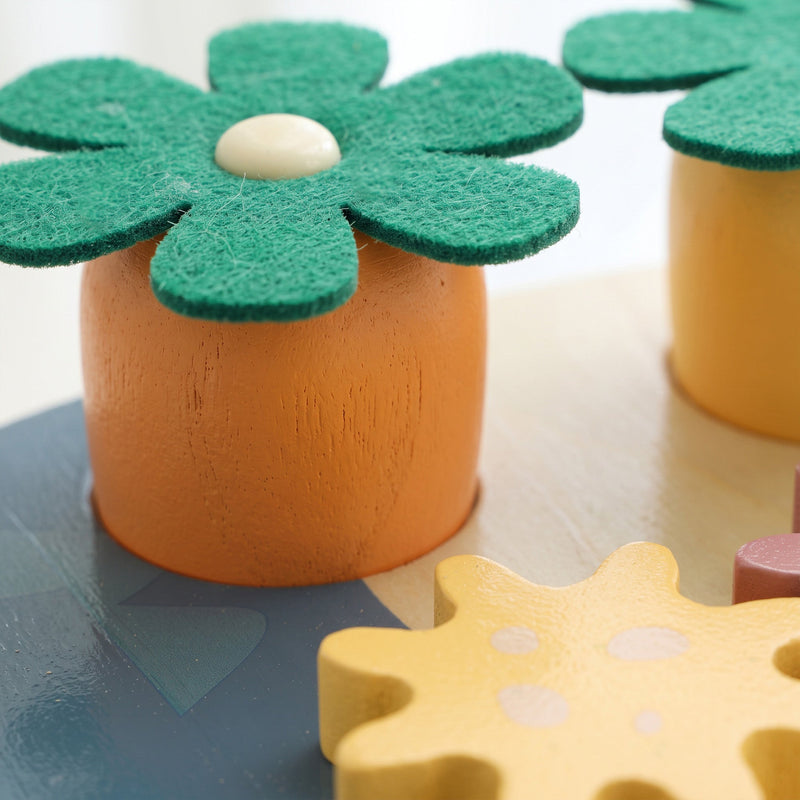Close-up of a green felt flower on an orange carrot piece and yellow gear
