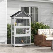 PawHut wooden bird cage on an outdoor patio beside garden furniture