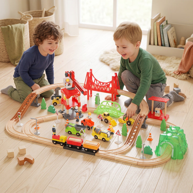 Two boys playing with the construction train set on a living room floor