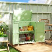 Light green shed on a decked patio with the lid raised and doors open showing a hose and tins