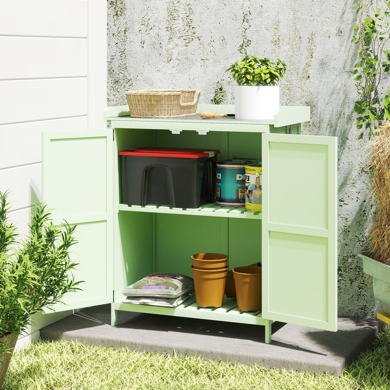 Light green shed with doors open and the worktop lifted, holding a basket, a plant, paint tins and pots