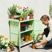 Man kneeling beside the light green shed planting into pots, with flowers arranged on the worktop