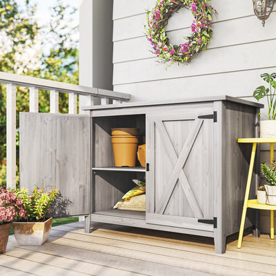 Light grey garden storage shed on a decked porch with one door open showing plant pots