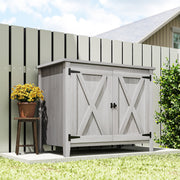 Light grey wooden storage shed standing on grass beside a painted garden fence