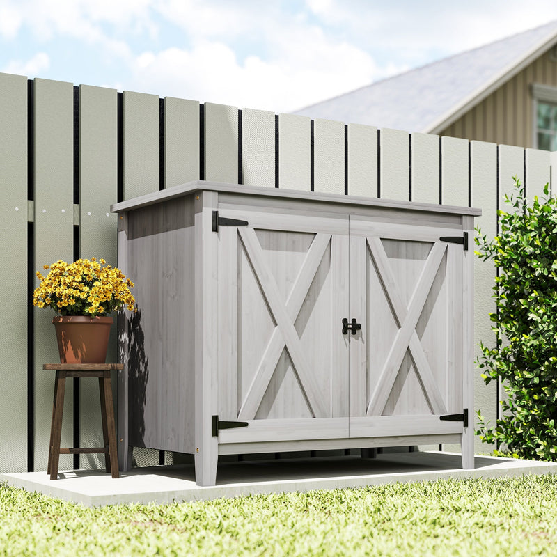 Light grey wooden storage shed standing on grass beside a painted garden fence