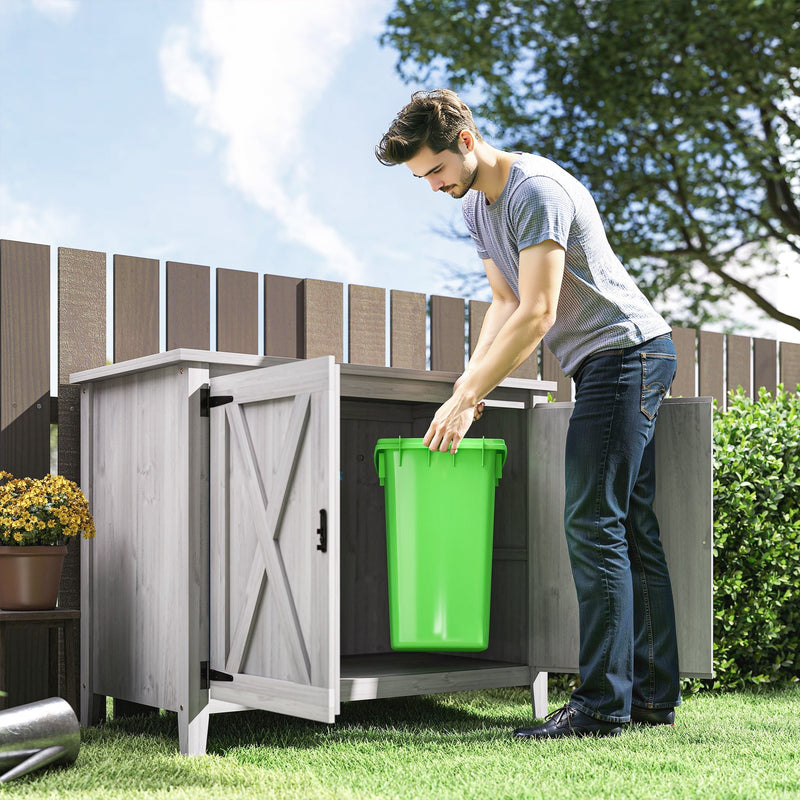 Man placing a green wheelie bin into the open light grey garden storage shed