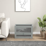 Grey hamster cage placed in a living room setting beside a sofa and plant