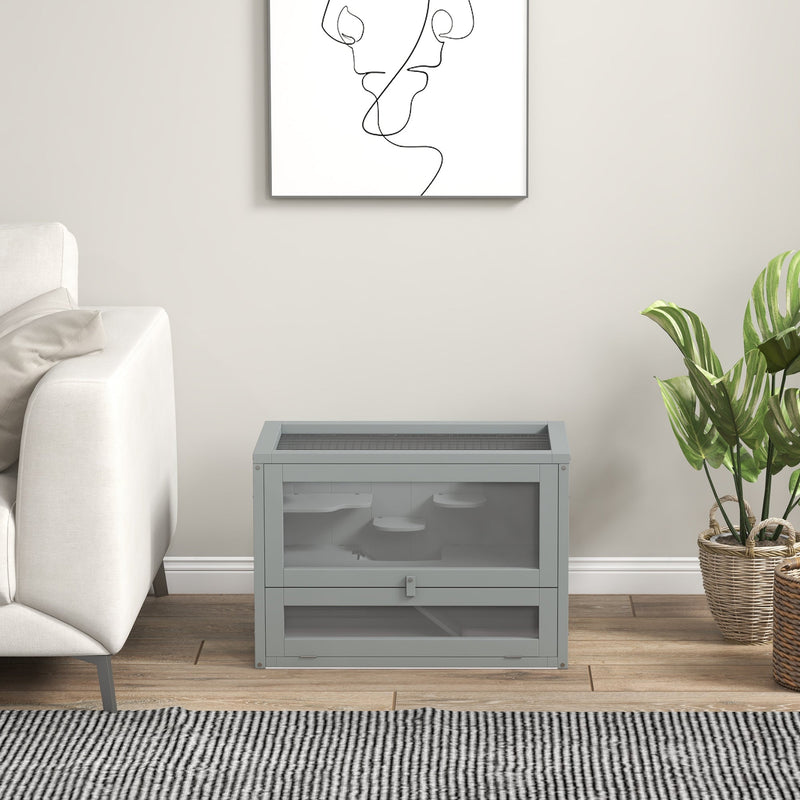 Grey hamster cage placed in a living room setting beside a sofa and plant