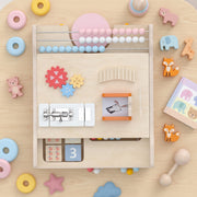 Flat-lay close-up of the activity board's abacus, gears, lock-and-latch and image-flip panel