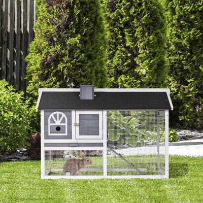 Rabbit hutch and run set up outdoors on grass with a rabbit inside the run area