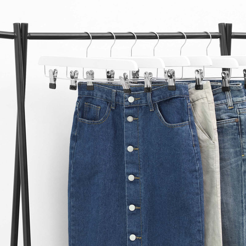 White wooden hangers on a chrome rail holding denim skirts and jeans