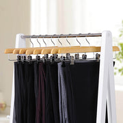 Natural wooden hangers on a white clothes rail holding dark trousers and skirts