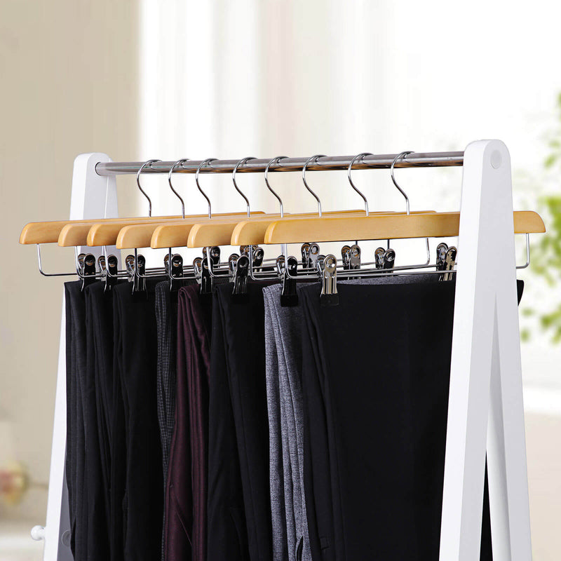 Natural wooden hangers on a white clothes rail holding dark trousers and skirts