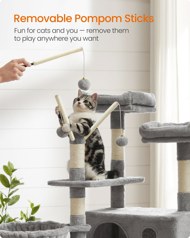 Hand holding a removable pompom stick while a cat reaches up the light grey cat tree