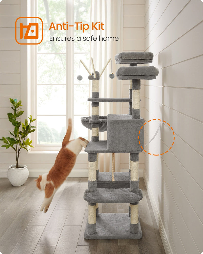 Cat jumping down from the light grey cat tree, which is secured with an anti-tip kit