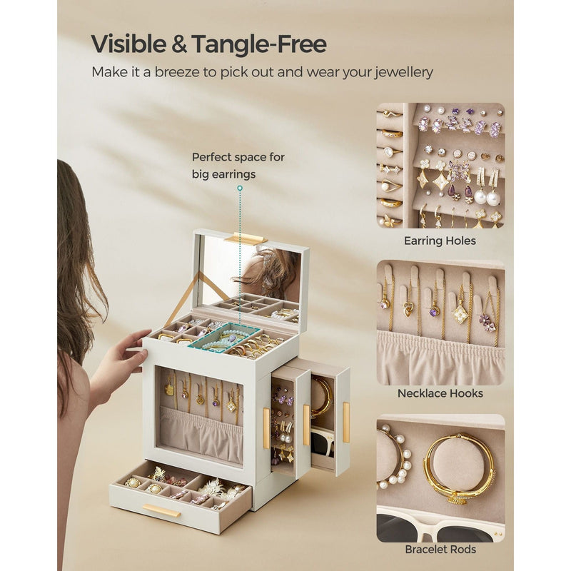 A woman opens the Dressing Table Jewellery Organiser in white, which boasts ample storage and includes various compartments. Its elegant design features a mirror, earring holes, necklace hooks, and bracelet rods. Ideal for any dressing table, it accommodates large earrings and its neutral color blends seamlessly with any décor.