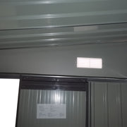 Interior wall of the shed showing a white louvred vent above the sliding door track