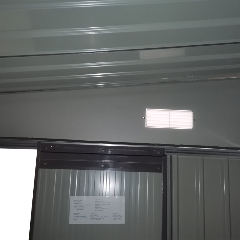 Interior wall of the shed showing a white louvred vent above the sliding door track